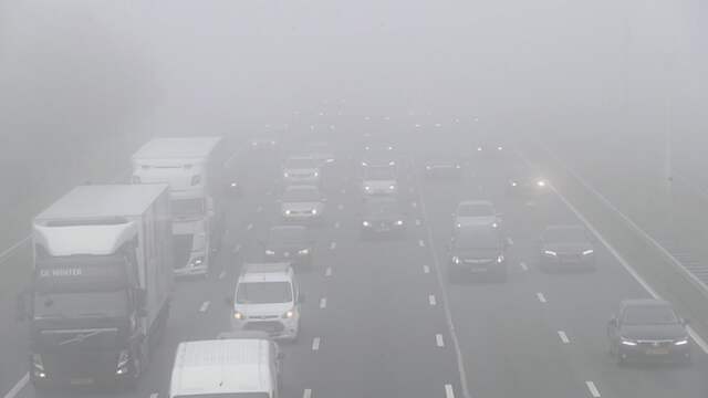 Automobilisten rijden in dichte mist op snelweg bij Schiphol