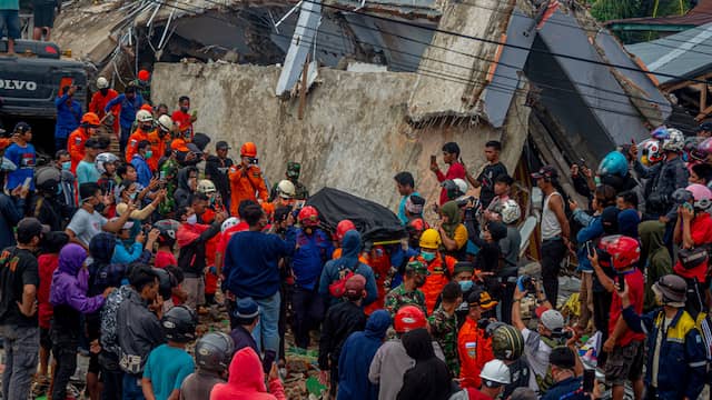 People are retrieving a victim from under the rubble in the city of Mamuju.