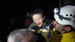 Syrisch jongetje lacht naar hulpverleners nadat hij gered is