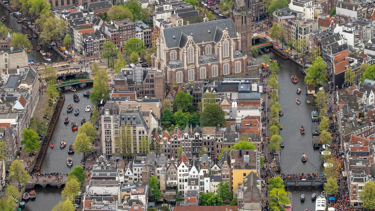 Luchtfoto van de Amsterdamse grachten, die gevuld zijn met bootjes met feestvierders.
