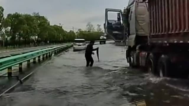Chinees vangt vis met zijn handen uit overstroomde weg