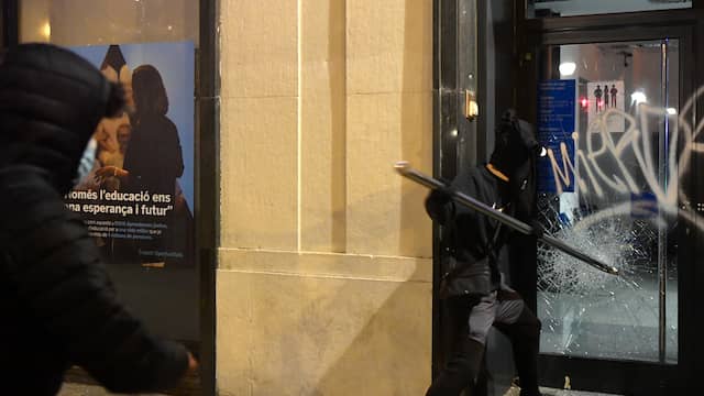 Een relschopper probeert de deur van een bankgebouw in de Catalaanse stad Barcelona in te slaan.