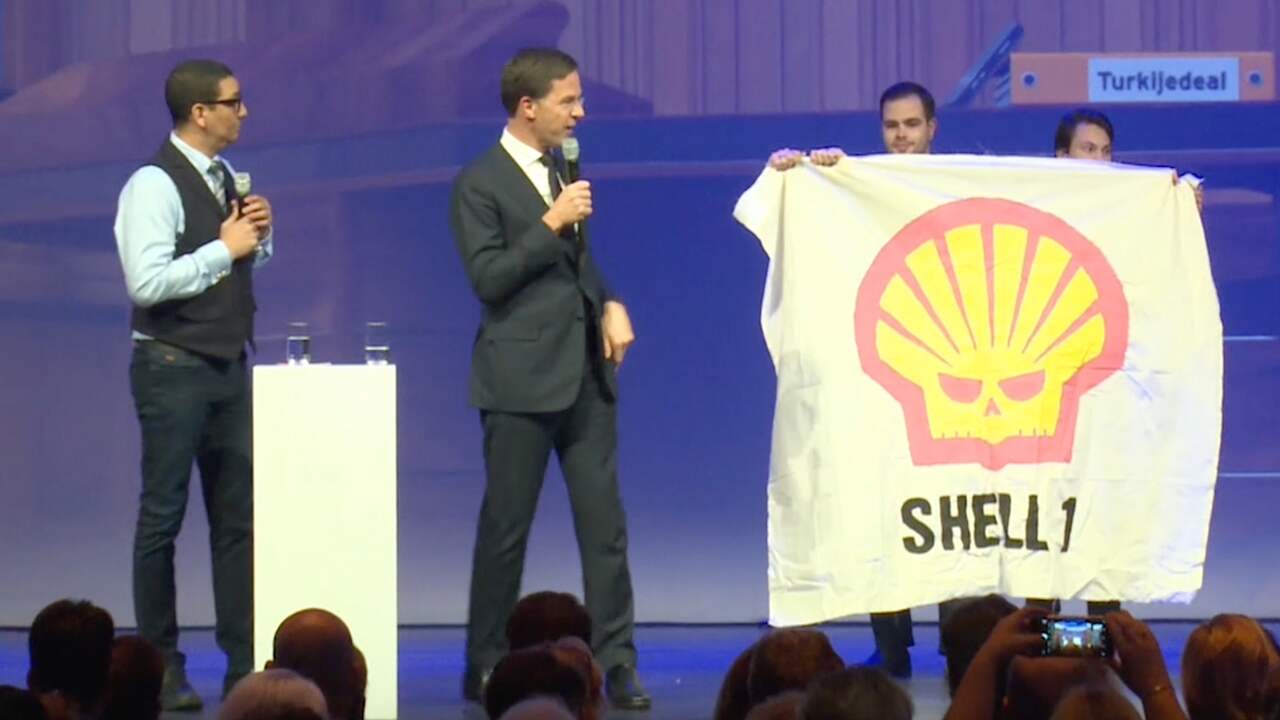 Beeld uit video: Demonstranten met spandoeken op podium tijdens optreden Rutte