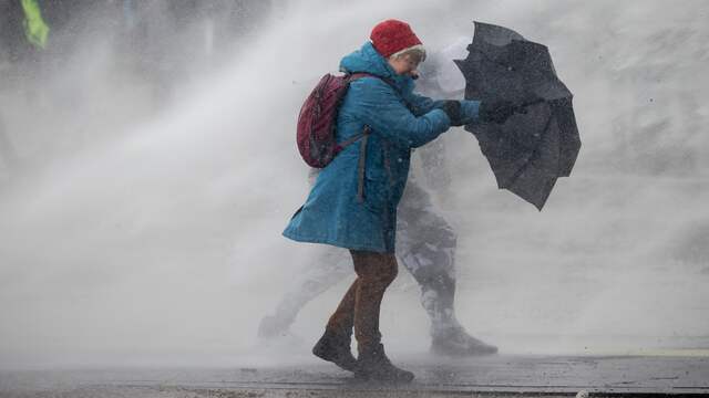 Paraplu's zijn niet opgewassen tegen de harde waterstralen die van de rijdende machines komen.