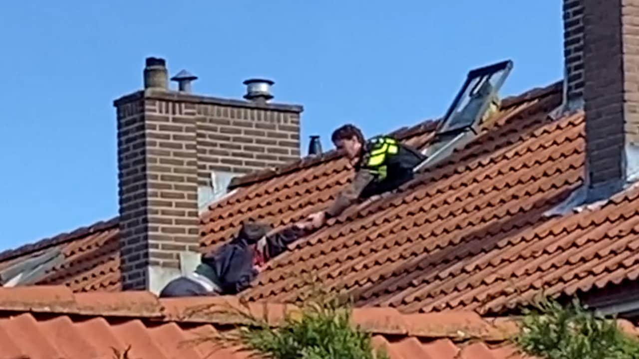 Beeld uit video: Politie redt oudere man die aan dak in Naaldwijk hangt