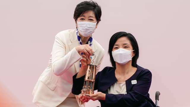 Gouverneur van Tokio Yuriko Koike en Aki Taguchi, ambassadeur van de fakkeltocht, met de olympische vlam in de lantaarn.