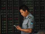 A security guard looks at his mobile phone in front of a screen displaying stock market figures at a securities company in Hangzhou in China's Zhejiang province on June 19, 2018. Shanghai and Hong Kong stocks plunged on June 19 on investors' fears that the US and China could be heading for a full-blown trade war following tit-for-tat tariff threats. / AFP PHOTO / - / China OUT
