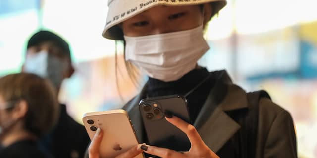 Een Chinese vrouw houdt een iPhone 12 en iPhone 12 Pro vast