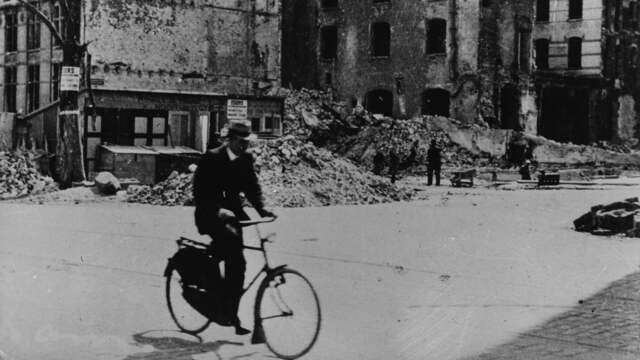 1941: Een fietser rijdt tussen de ruïnes in Rotterdam.