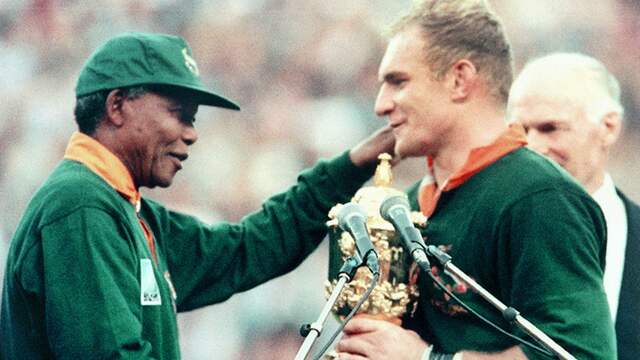 Zuid-Afrika mocht pas na de afschaffing van de apartheid weer meedoen aan grote sportevenementen. Dat leverde na de finale van het WK rugby in 1995 deze beroemde foto op met president Nelson Mandela en aanvoerder Francois Pienaar.