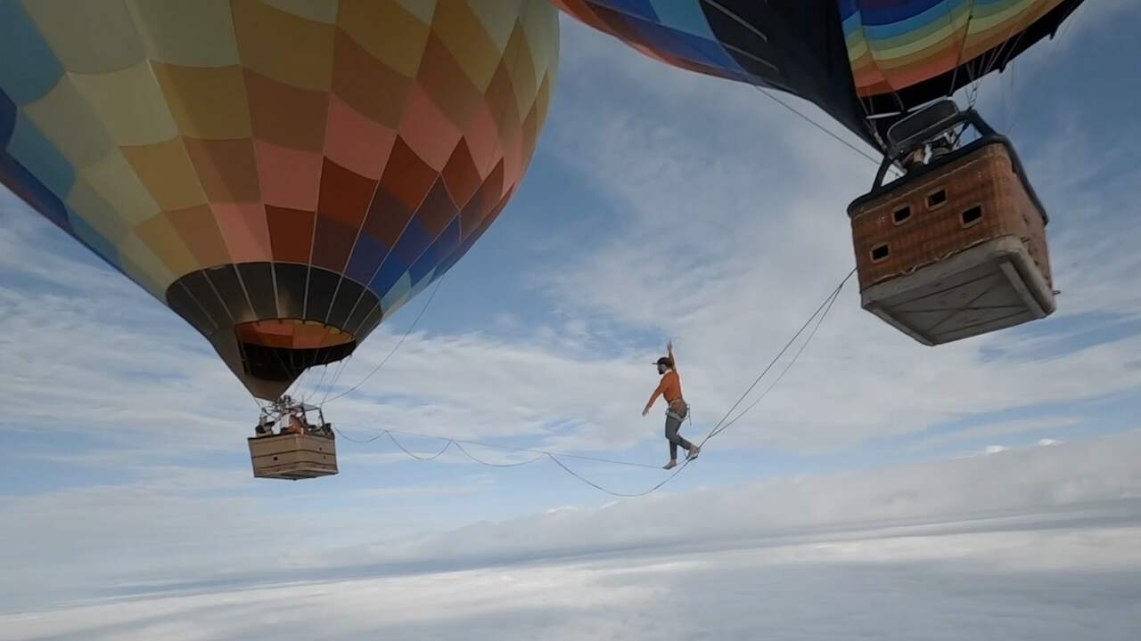 Beeld uit video: Waaghals loopt over touw tussen twee luchtballonnen