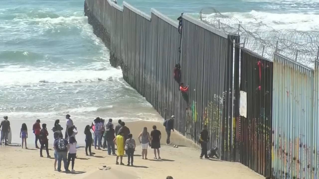 Beeld uit video: Migranten klimmen over hoge grensmuur tussen Mexico en VS