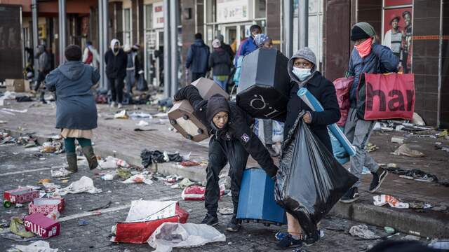Mensen zoeken naar spullen in een geplunderd winkelcentrum in township Vosloorus (Gauteng)