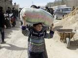 Donderdag 15 maart: Een Syrische jongen tilt in Oost-Ghouta een zak op zijn hoofd.