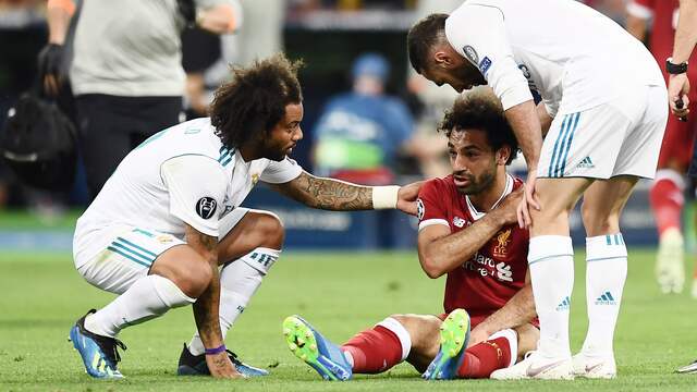 Mohamed Salah zit met een pijnlijke schouder op de grond na een overtreding van Sergio Ramos.