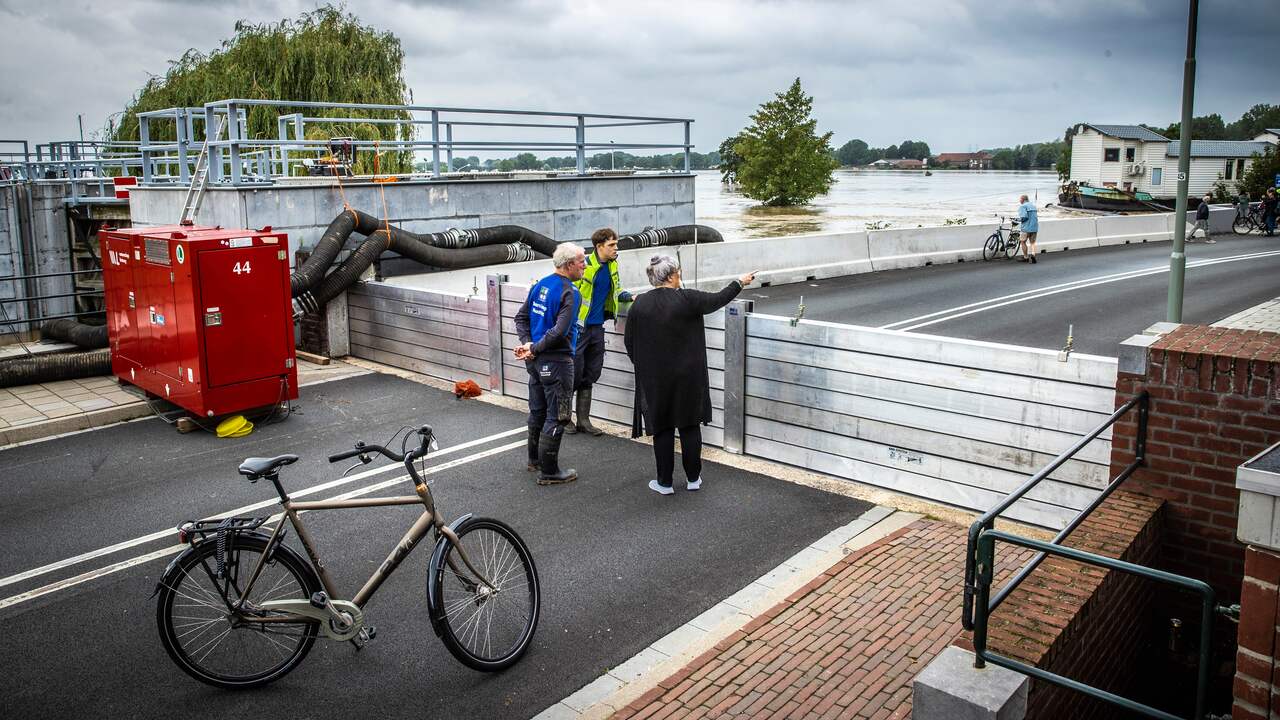 Mensen staan te kijken naar het hoge water bij een gesloten coupure waar de Roer in de Maas stroomt in het centrum van Roermond.