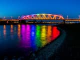 Maandag 3 april: De brug over de IJssel bij Westervoort is aangelicht in regenboogkleuren. De buurgemeente van Arnhem doet dit uit protest tegen de mishandeling van twee homoseksuele mannen in die stad. 