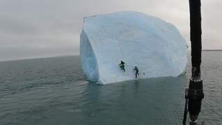 Iceberg tilts atop adventurers while climbing