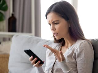 Vrouw kijkt verward of geïrriteerd naar smartphone
