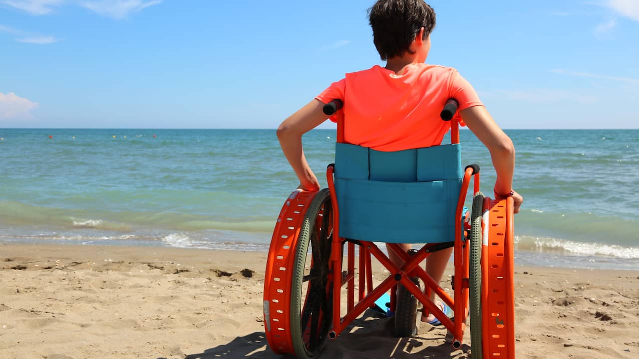 Инвалидная коляска на пляже лицом к камере