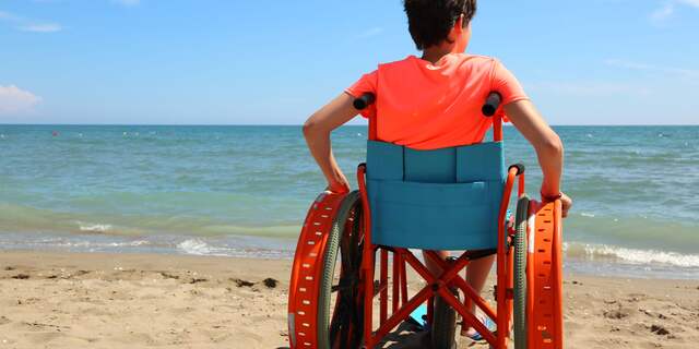 kind in rolstoel op strand