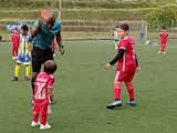 Scheidsrechter geeft peuter die voetbalveld oprent lachend een rode kaart