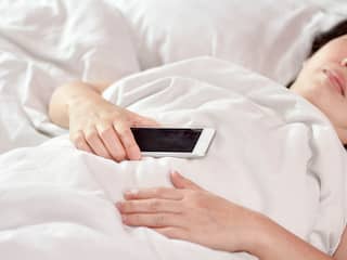 vrouw in bed met smartphone in hand