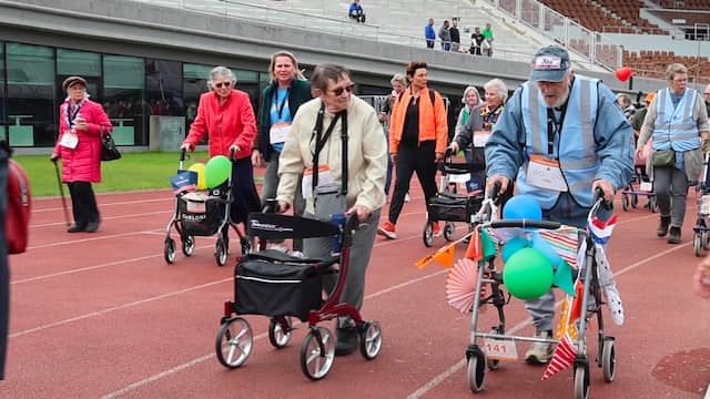 Senioren lopen met rollator over atletiekbaan in Olympisch Stadion