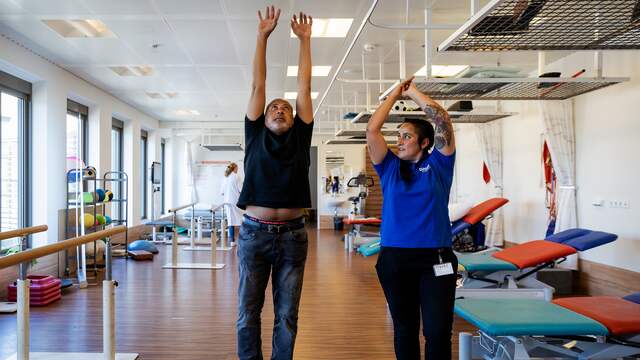Een voormalig coronapatiënt die in een revalidatiecentrum aan zijn herstel werkt.