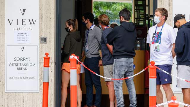 Spelers, coaches, officials en stafleden staan in de rij voor een coronatest.