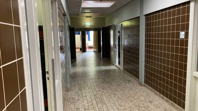 De gang in de barak waaraan de slaapkamers van de evacués grenzen.