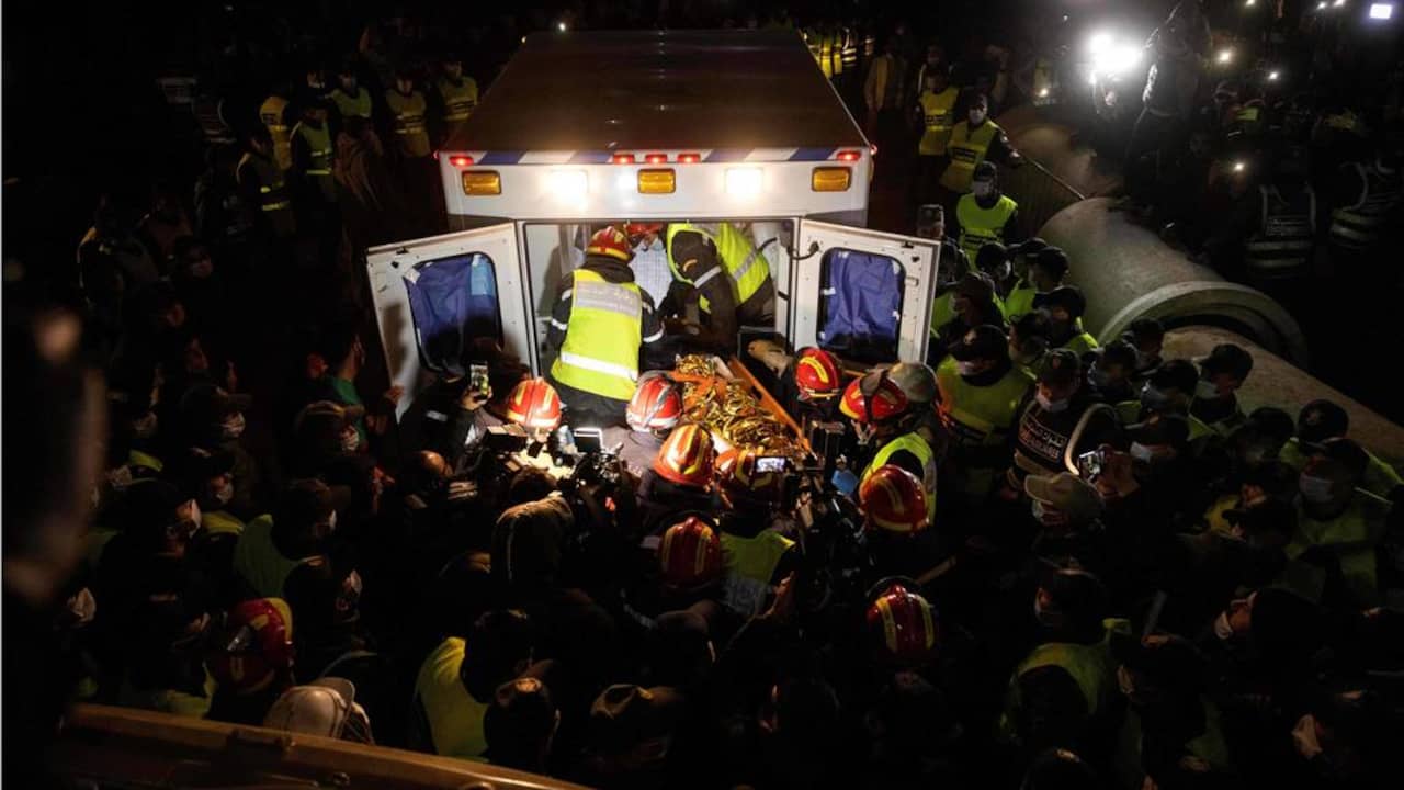 Het lichaam van de kleine Rayan wordt door hulpverleners de ambulance in gedragen.
