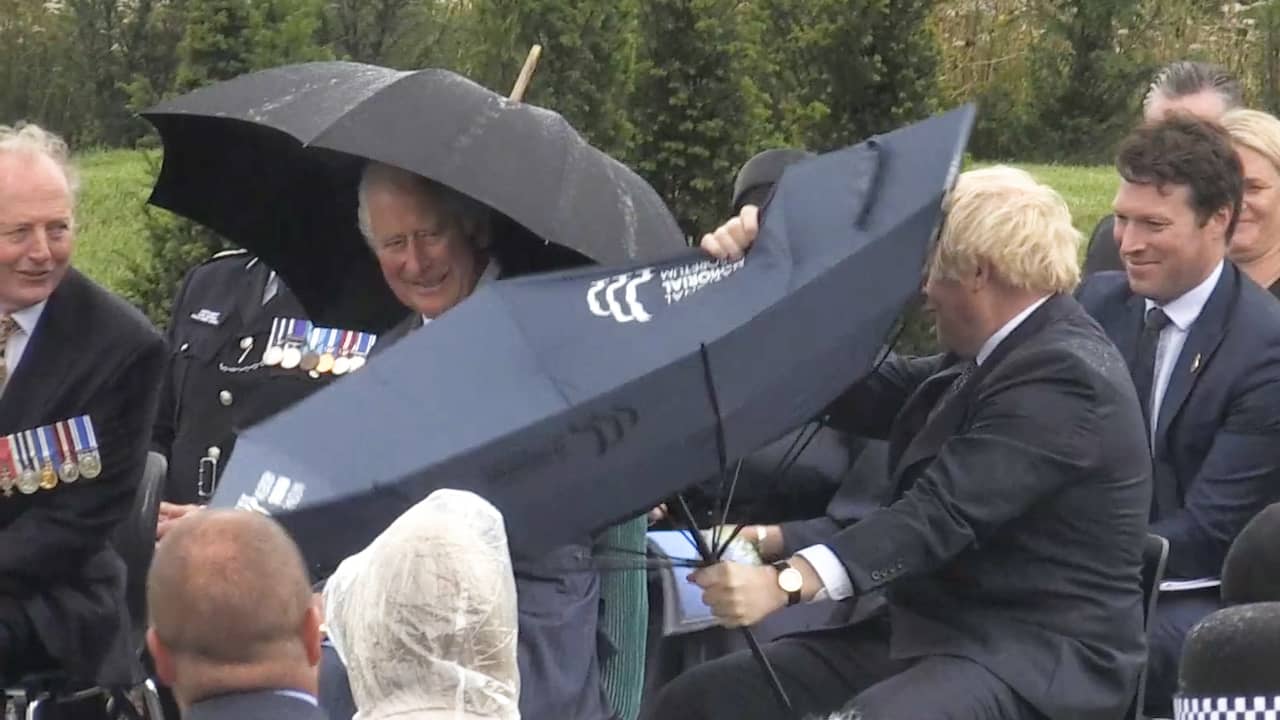 Beeld uit video: Prins Charles lacht als Britse premier Johnson met paraplu worstelt