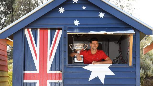 Novak Djokovic liet zijn trofee maandag op het strand van Melbourne zien.