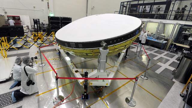 Amerikaanse wetenschappers werken aan een satelliet, die door zijn vorm op een vliegende schotel lijkt.