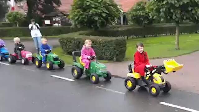 Kinderen rijden op speelgoedtrekkers in protestoptocht