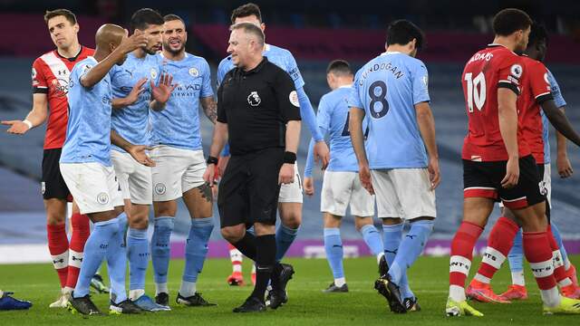 Spelers van Manchester City vragen om een strafschop bij scheidsrechter Jon Moss.