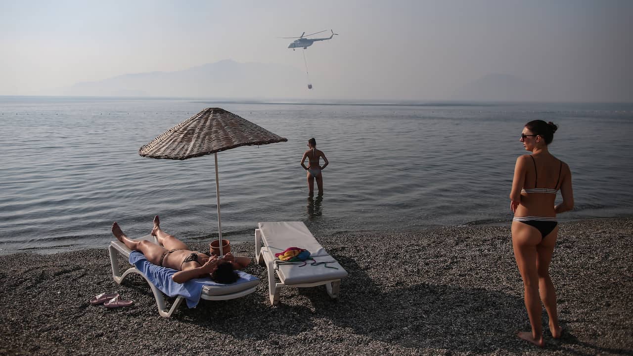 Toeristen in de Turkse badplaats Marmaris zien hoe een blushelikopter water uit de zee schept.