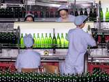 NB: uit 2002! CHINA, QINGDAO : Workers inspect bottles of beer rolling out from the Qingdao Brewery plant in the eastern port city of Qingdao, 18 February 2002. Qingdao Brewery Co., the producer of China's most famous beer Tsingtao, wants to become one of the world's top 10 beer makers within the next year and a half to coincide with the company's 100th anniversary in August 2003, amids a rapid expansion drive fueled by an aggressive merger campaign. AFP PHOTO