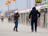 Wandelaars trotseren de storm en stuifzand op de boulevard van Scheveningen