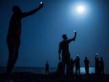 De winnende foto van de Amerikaan John Stanmeyer. Een groep Afrikaanse migranten in de nacht aan de kust van Djibouti-stad houdt telefoons in de lucht in een poging familie  in buurland Somalië te kunnen bellen.