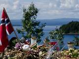 Bloemen en kaarsen met op de achtergrond de punt van het eiland Utoya in Oslo.