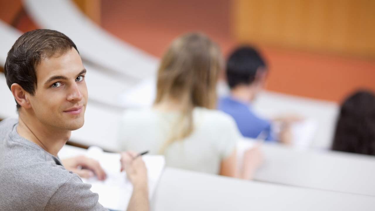 Student pay. Улыбчивая студент. Отвлекающийся студент. Молодые студенты оглянулись. Красивая пара рядом в студенческой аудитории фото