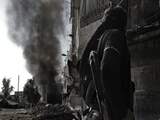 Zondag 28 oktober: Een Syrische rebel kijkt naar de rook die uit een in brand gestoken bus komt. 
