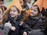 Kinderen dragen oranje zelfgemaakte mutsen tijdens de presentatie van de Koningsspelen.