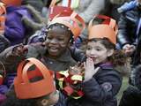 Kinderen dragen oranje zelfgemaakte kronen tijdens de presentatie van de Koningsspelen.