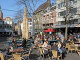 Door het zonnige weer is het gezellig druk op dit terras aan de Grote Marktstraat in Den Haag.