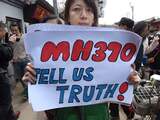 Een familielid van een Chinese passagier van het vermiste MH370-toestel houdt een affiche vast bij het verlaten van de Yonghegong Lama tempel in Peking.