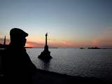 A man looks at vessels cruising in the harbor of Sevastopol at sunset on March 5, 2014. A UN envoy sent to Ukraine's tense Crimea region, Robert Serry, decided to cut short his mission on March 5 after he was threatened by unidentified gunmen, an assistant traveling with him told AFP. Serry, who was in the Black Sea peninsula to assess the situation for the United Nations, was on his way to the airport immediately after a confrontation with gunmen outside the naval headquarters in Crimea's capital of Simferopol. AFP PHOTO/Filippo MONTEFORTE