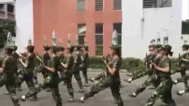 Chinese cadetten balanceren waterflessen op hoofd tijdens marcheren
